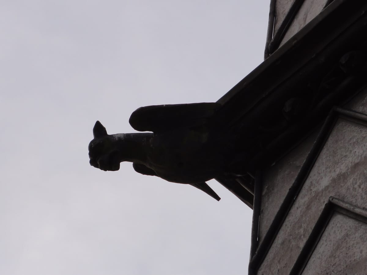 A gargoyle at roof level, in silhouette against a fen sky A gargoyle at roof level, in silhouette against a fen sky